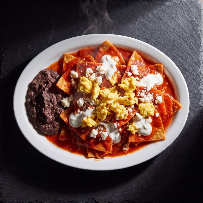 Chilaquiles Entomatados, seen from above on a white plate.