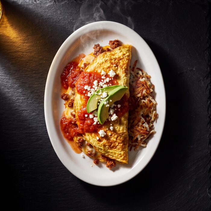 A Mexican omelette with chorizo and melted cheese, seen from above on a white plate.